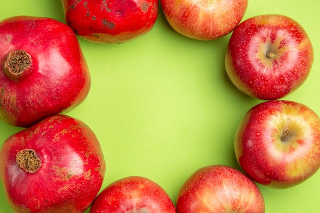 Top close-up view fruits the appetizing pomegranates and apples are laid out in a circle