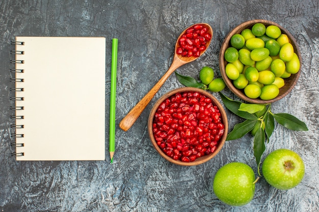 Top close-up view fruits apples citrus fruits seeds of pomegranates pencil notebook