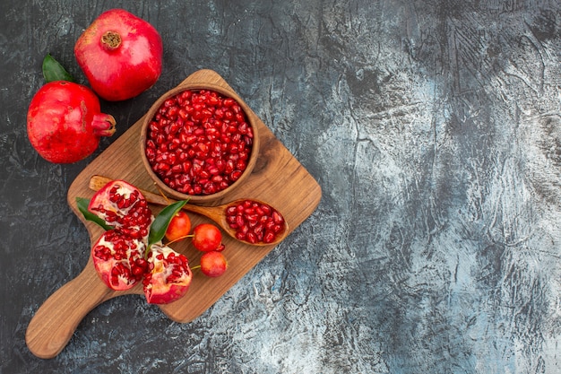 Free photo top close-up view fruits the board with pomegranate seeds spoon peeled pomegranate cherries