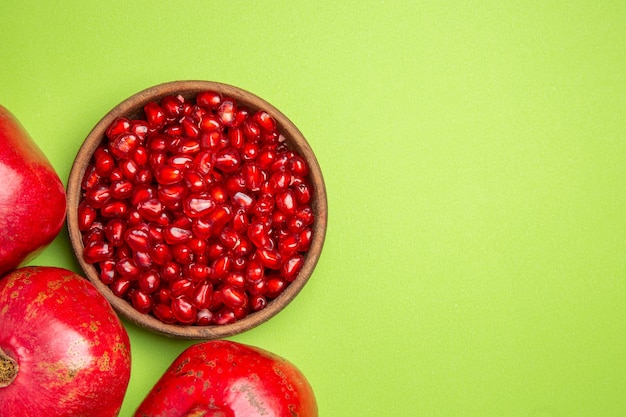 Free photo top close-up view fruits bowl of seeds of pomegranate on the green table