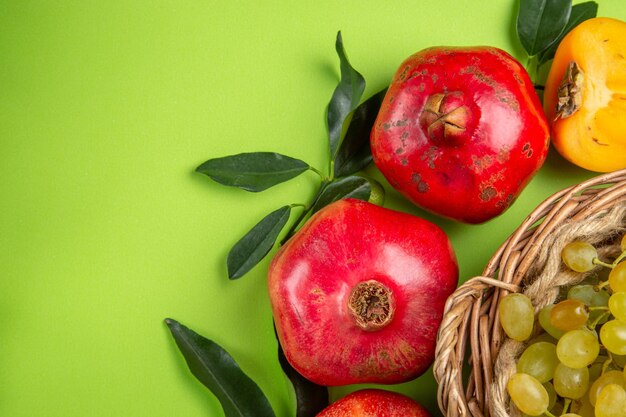 Top close-up view fruits pomegranates persimmon bunches of grapes and leaves