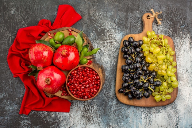 Top close-up view fruits pomegranates on the red tablecloth and bunches of grapes on the board