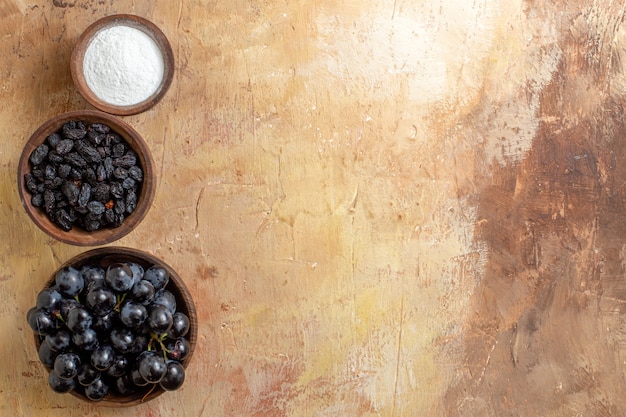 Free Photo top close-up view grapes black grapes sugar raisins in the brown bowls