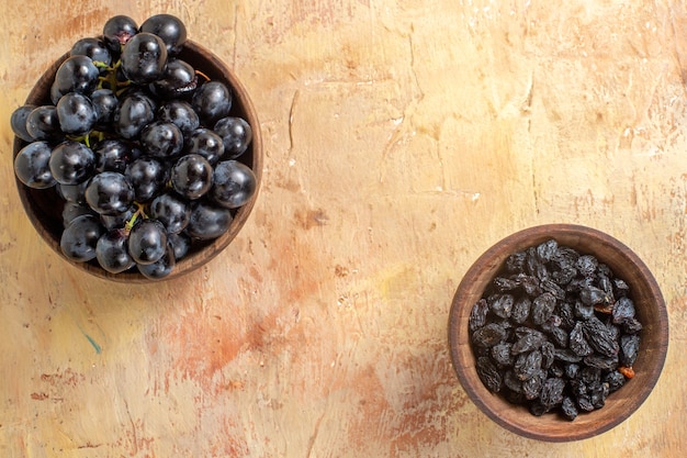 Top close-up view grapes bowls of black grapes and raisins on the table