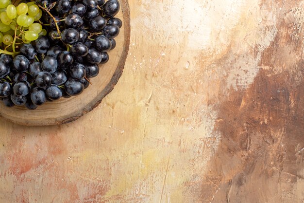 Top close-up view grapes bunches of black and green grapes on the wooden cutting board