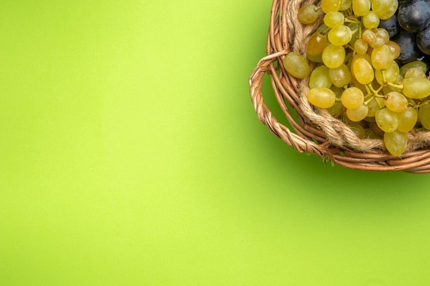 Free photo top close-up view grapes bunches of grapes in the wooden basket on the green background