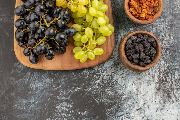 Top close-up view grapes dried fruits the cutting board with bunches of the tasty grapes