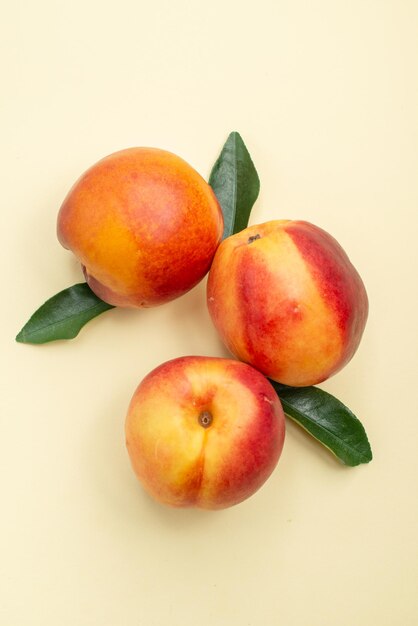 Top close-up view nectarine three nectarines with leaves on the white surface