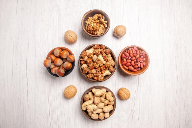 Top close-up view nuts five brown bowls of nuts in the center of white table