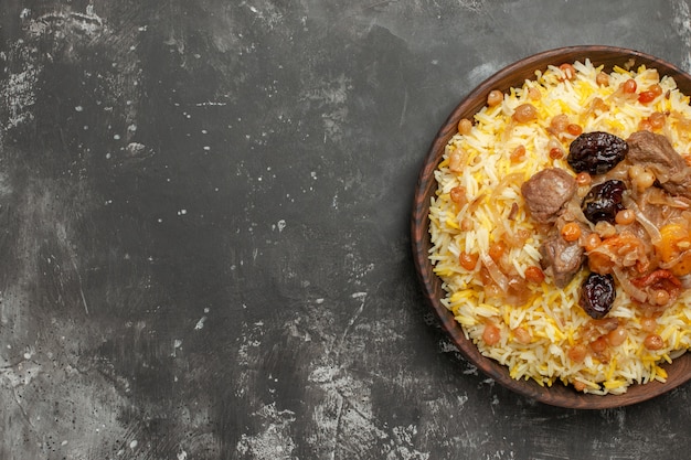 Top close-up view pilaf an appetizing pilaf with meat dried fruits in the brown bowl