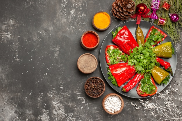 Top close-up view plate of peppers peppers with herbs on the plate spices cones Christmas tree toys