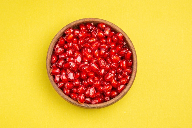 Free photo top close-up view pomegranate bowl of seeds of the appetizing pomegranate on the yellow table