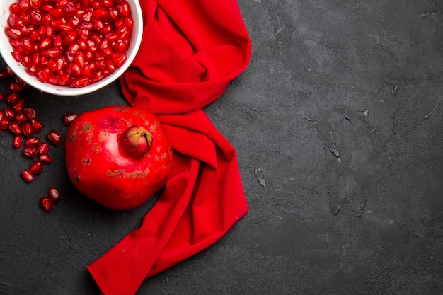 Free Photo top close-up view pomegranate pomegranate next to the pomegranate seeds in the bowl red tablecloth