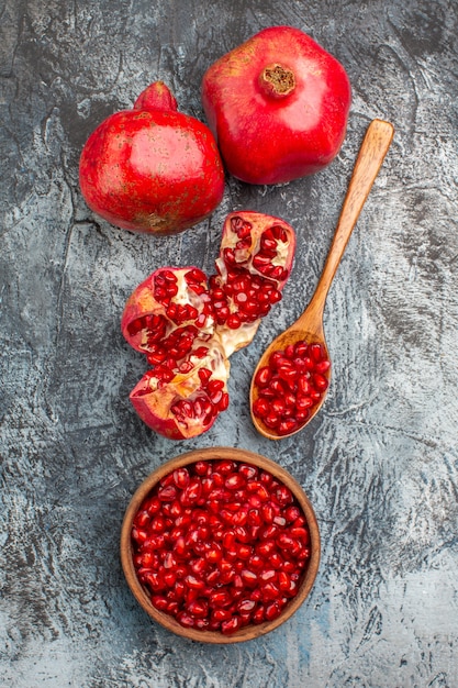 Free photo top close-up view pomegranate two pomegranates peeled pomegranate spoon pomegranate seeds