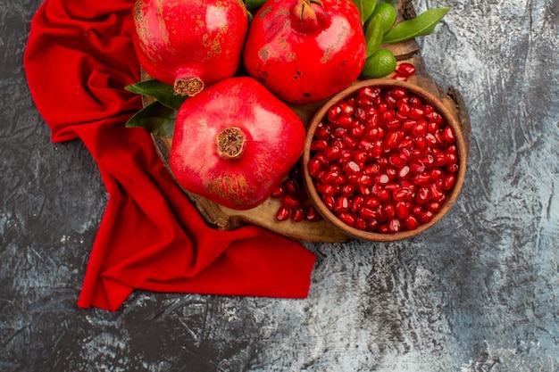 Top close-up view pomegranates wooden cutting board with pomegranate seeds and pomegranate