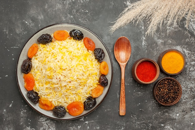 Free Photo top close-up view rice plate of rice with dried fruits spoon colorful spices