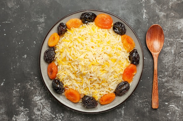 Free photo top close-up view rice spoon the appetizing dried fruits and rice in the plate on the table