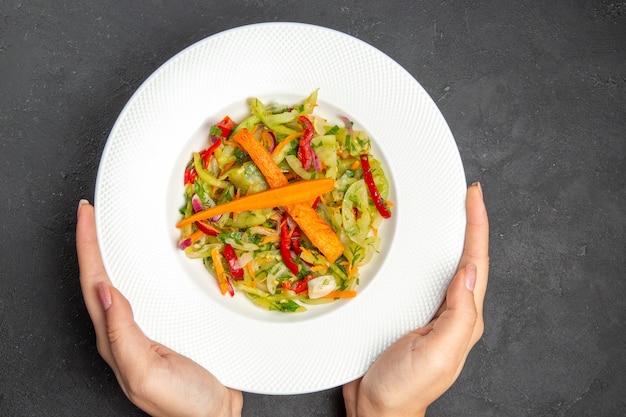 Free photo top close-up view salad plate of an appetizing salad with vegetables in hands