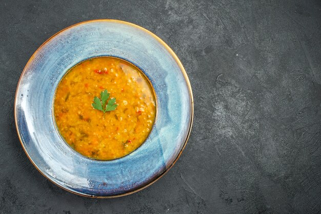 Top close-up view soup plate of an appetizing soup with herbs on the table