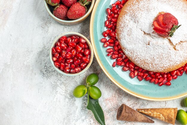 Top close-up view sweets a cake with pomegranate citrus fruits bowls of strawberries pomegranate