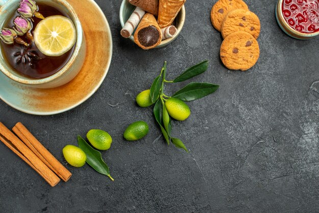 Top close-up view sweets cookies jam waffles a cup of tea with lemon citrus fruits