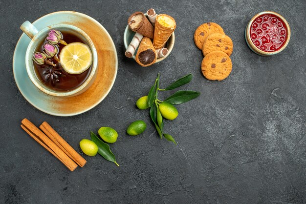 Top close-up view sweets waffles in bowl a cup of tea cookies cinnamon jam citrus fruits