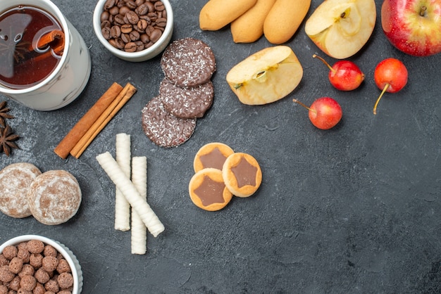 Top close-up view tea a cup of tea star anise coffee beans apples cherries cookies