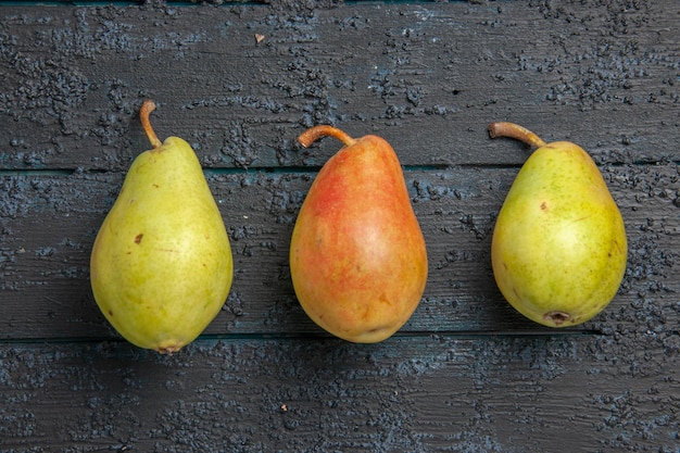 Free Photo top close-up view three pears on table two green pears and one red-yellow pear in the center of grey table