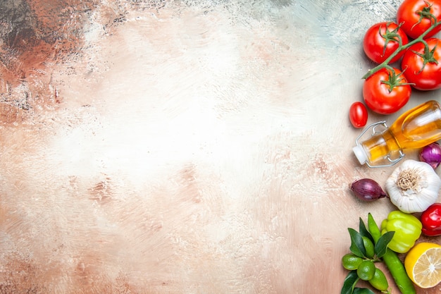 Top close-up view vegetables tomatoes with pedicels garlic bell peppers lemon oil onion