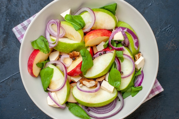 Top close view apple salad in bowl purple and white checkered napkin on dark table