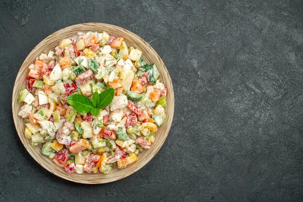 Top close view of bowl of vegetable salad on the left side with green on it on dark green background