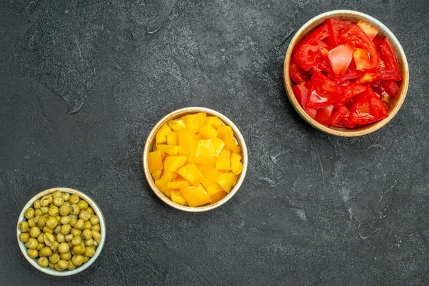 Top close view of bowls of vegetables on dark grey background