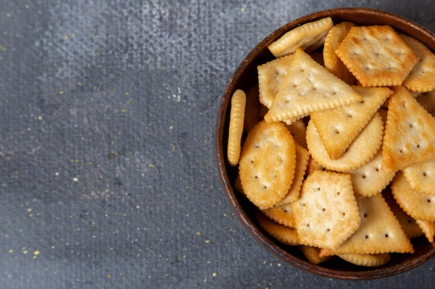 Top close view brown metallic plate with salted crackers inside on the grey background crisp cracker snack photo