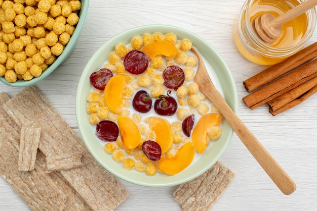 Top close view cereals with milk inside plate with crackers cinnamon and honey on white, drink milk dairy creamery breakfast