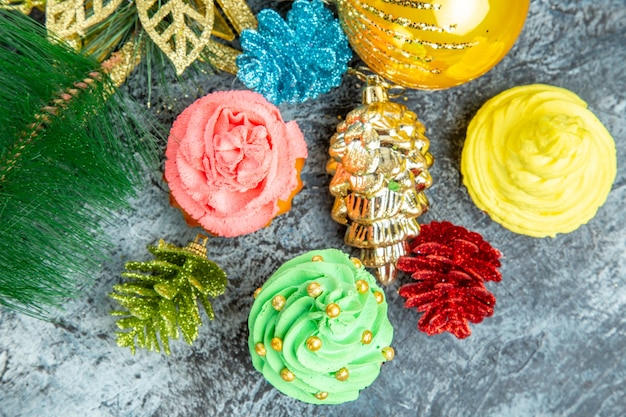 Free photo top close view colorful cupcakes xmas ornaments on grey background