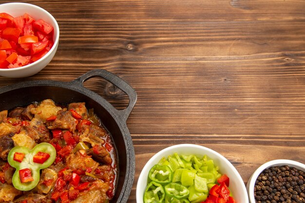 Top close view cooked vegetable meal with sliced bell-pepper salad on brown surface