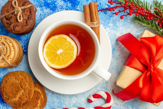 Top close view cup of tea cookies tied up with rope giftbox on blue table