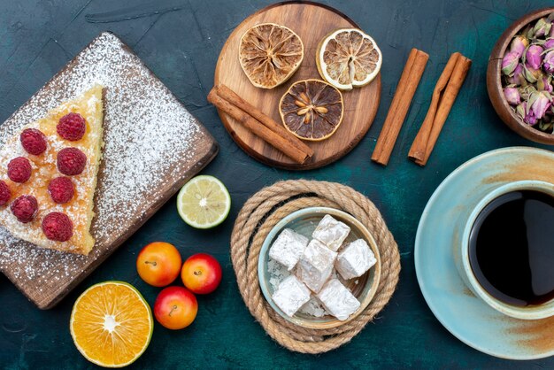 Top close view delicious cake slice with tea cinnamon and fruits on the dark-blue desk pie cake sweet biscuit sugar