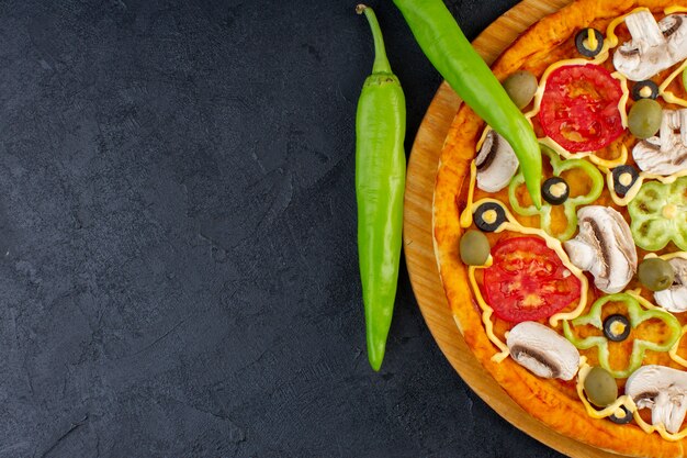 Top close view delicious mushroom pizza with red tomatoes bell-peppers olives and mushrooms all sliced inside on the dark background food pizza italian