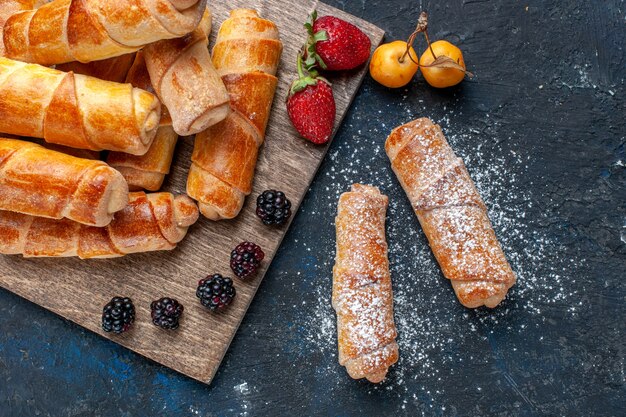 Top close view of delicious sweet bangles with filling yummy baked with fruits on dark, bake cake biscuit sugar sweet dessert