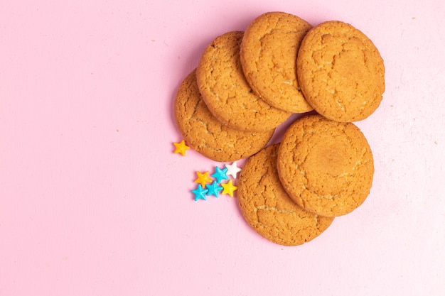 Top close view delicious sweet cookies baked lined on the pink background