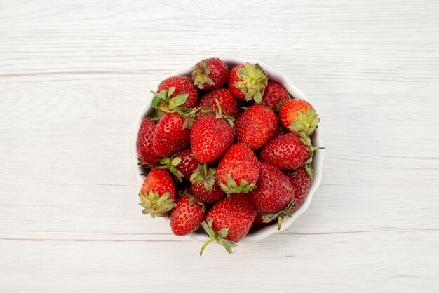 Top close view of fresh red strawberries mellow and delicious berries inside white plate on light , fruit berry fresh red color