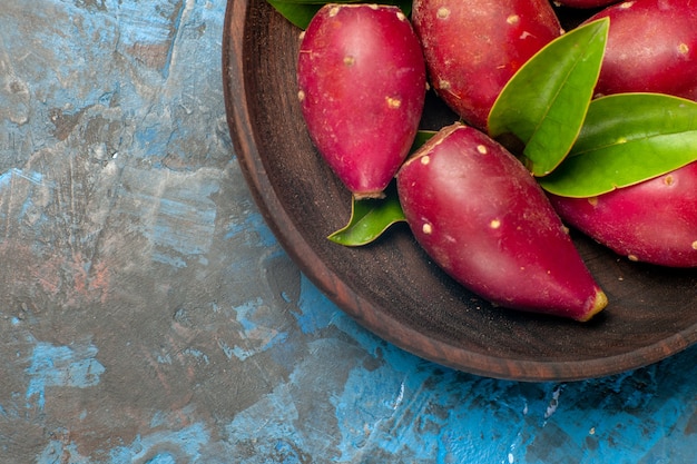 Top close view fresh ripe plums inside wooden plate on blue background tree sour fruit photo color mellow