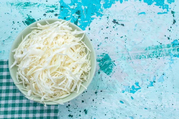 Top close view of fresh sliced cabbages inside round plate on bright-blue desk, vegetable food meal healthy salad