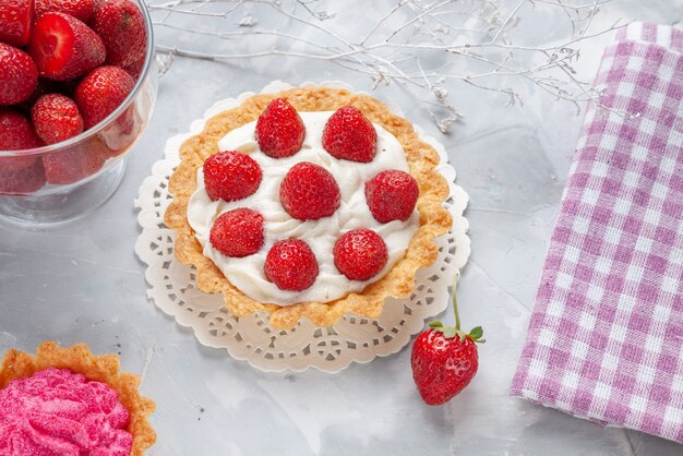 Top close view of little cake with cream and fresh red strawberries pink cream cake on white desk, cake fruit berry biscuit cream