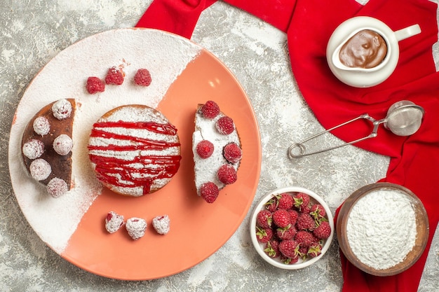 Top close view of plate of sweet with berries flour tea sieve and chocolate over red napkin on side on marble background