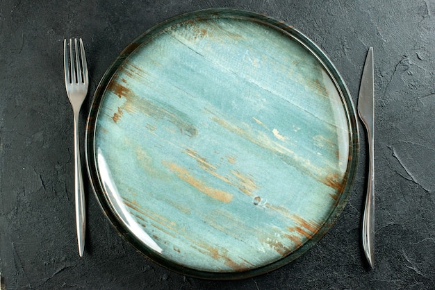 Top close view round platter dinner knife and fork on black table