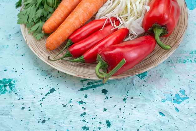 Free photo top close view of vegetable composition cabbage carrots greens and red spicy peppers on bright-blue desk