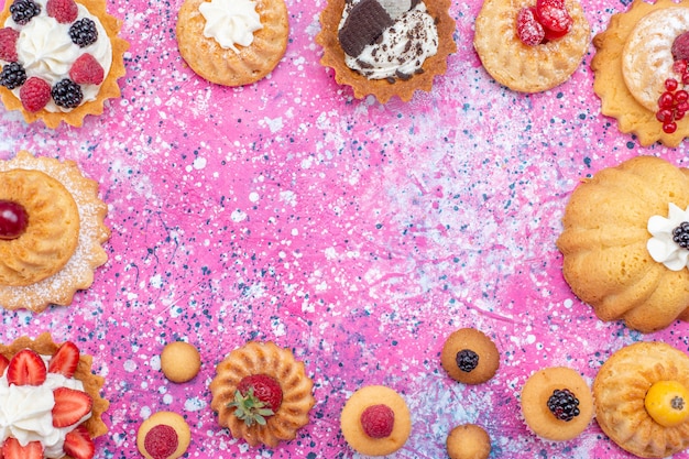 top closer view of baked yummy cakes with cream along with different berries on light