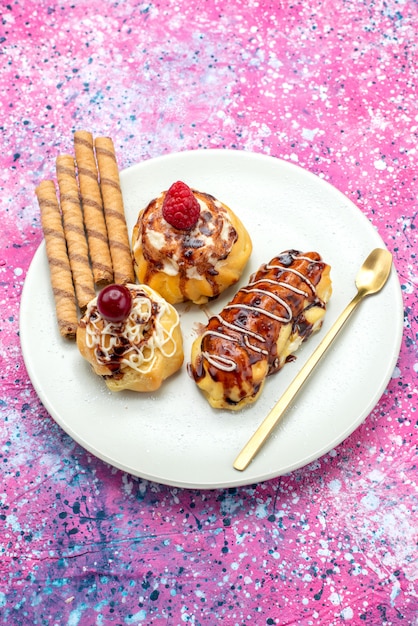 Free photo top distant view delicious fruity cakes with cream and chocolate inside white plate on the pink background cake biscuit sweet bake